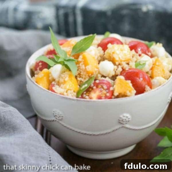 A vibrant Peach Quinoa Caprese Salad in a white serving bowl, showcasing its colorful ingredients and fresh appearance.