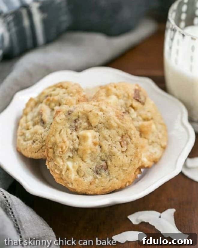 A beautiful white ceramic bowl brimming with a fresh batch of homemade White Chocolate Toffee Chunk Oatmeal Cookies, ready for serving at a party.
