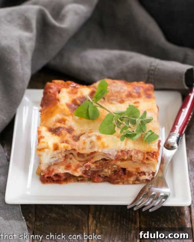 Lasagna with Italian Sausage on a white plate with a red handled fork.
