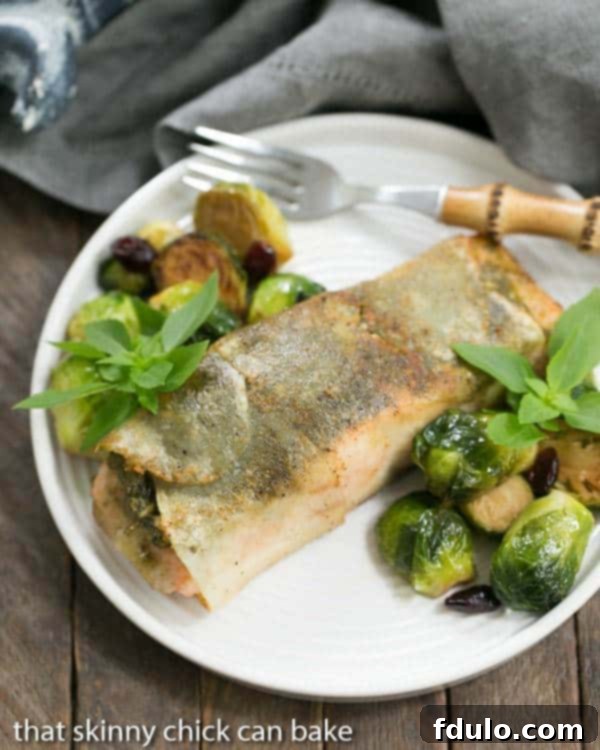 Potato Shingled Salmon on a white plate with brussels sprouts, showcasing the crispy potato crust and flaky salmon