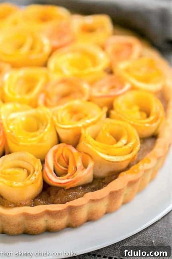 Close up view of Rosette Apple Tart on a white cake plate, highlighting the vibrant colors and detailed arrangement.