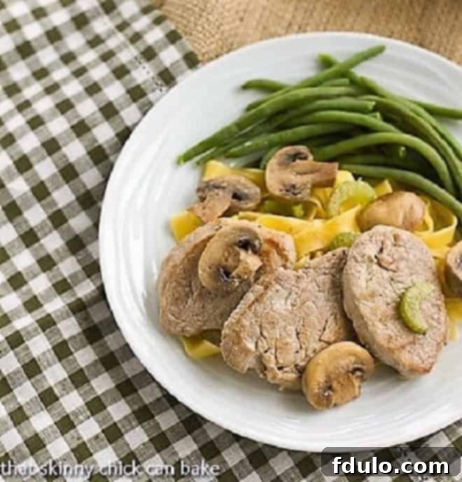 Overhead view of Pork Scaloppine over egg noodles on a white dinner plate