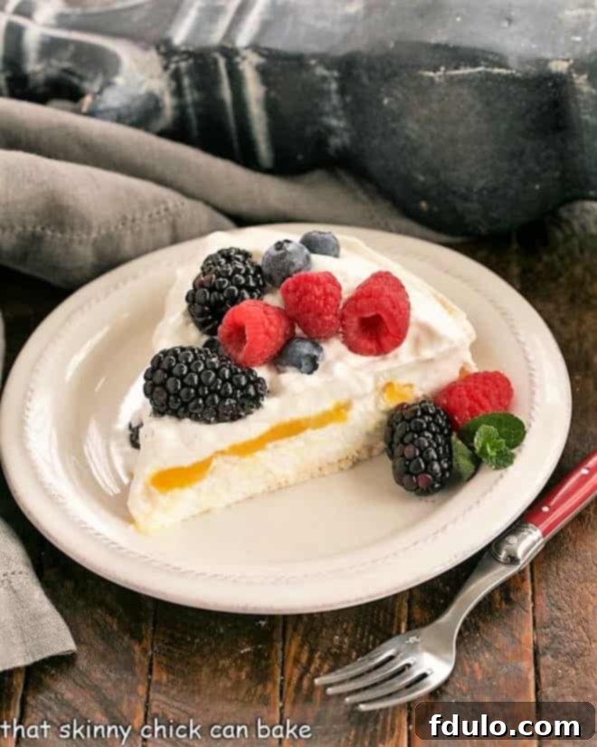 Slice of lemon Pavlova topped with berries on a white dessert plate