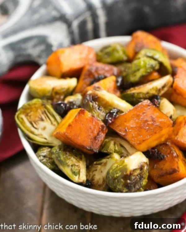 Roasted Fall Vegetables - Squash, Brussels sprouts and dried cranberry party together for a magnificent side dish! Roasted Autumn Vegetables in a white basketweave bowl, showcasing vibrant colors of squash, Brussels sprouts, and cranberries.