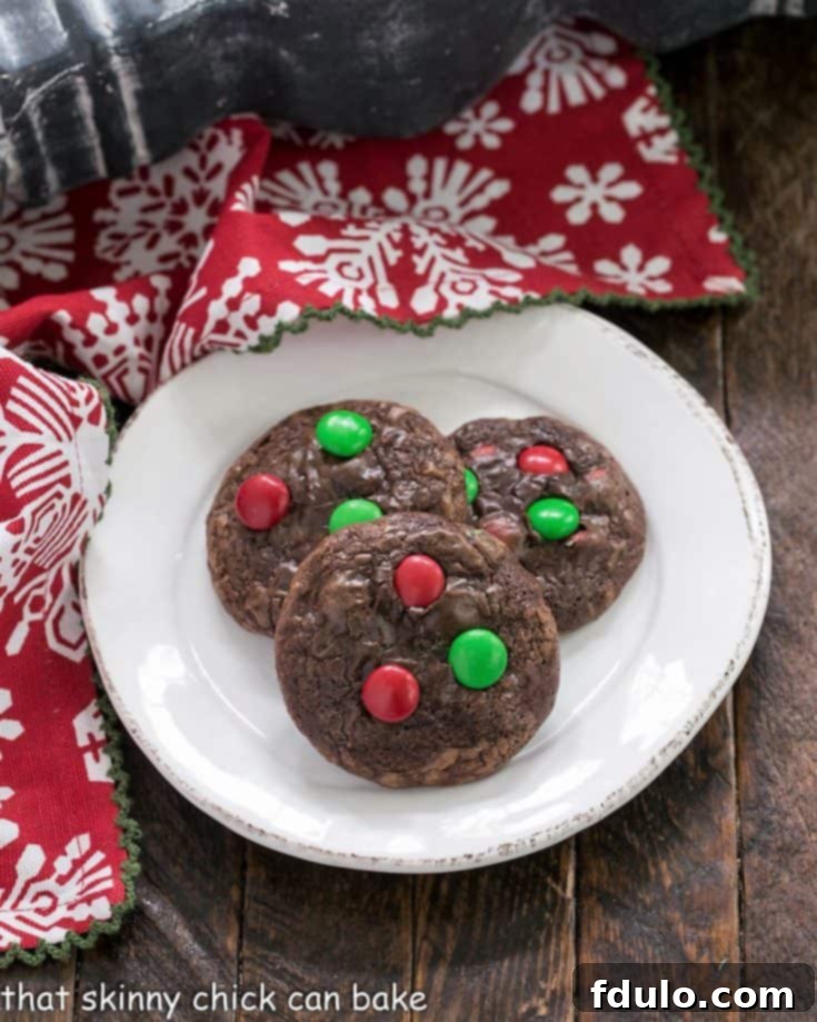 Overhead view of 3 holiday truffle cookies on a small white plate, garnished with festive red and green M&M's, ready to be enjoyed.
