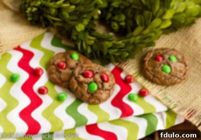 Two freshly baked Holiday Truffle Cookies resting on a festive patterned napkin, perfectly showcasing their fudgy texture and colorful M&M's, inviting a delightful bite.