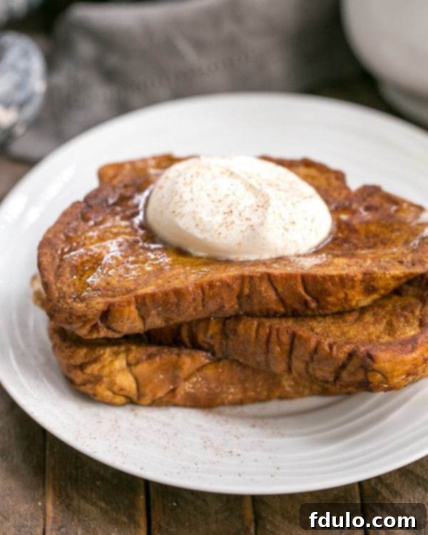 A beautifully arranged plate of Pumpkin French Toast, garnished with fresh berries and mint leaves, ready for a delightful fall breakfast.