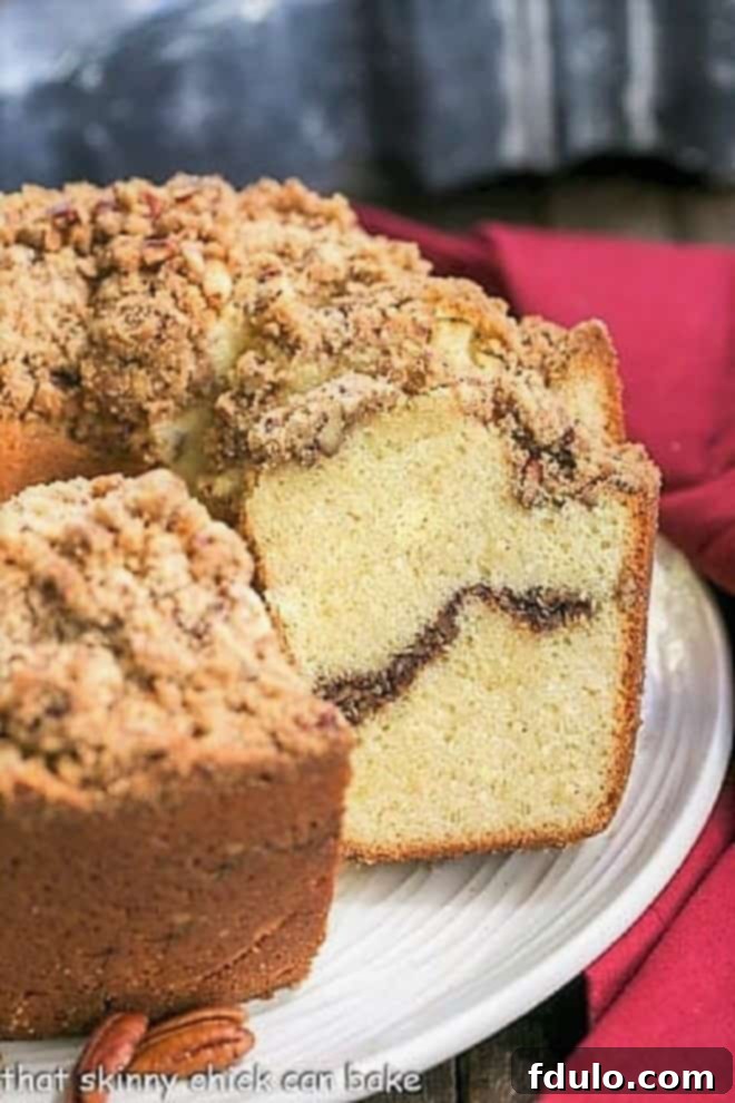 A beautifully baked Streusel Coffee Pound Cake presented on a round white serving plate, showcasing its golden-brown crust and inviting streusel topping.