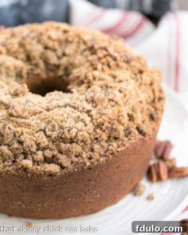 A close-up view of a Streusel Coffeecake Pound Cake slice on a white plate, showcasing the top covered with golden crumbs and the moist cake texture.