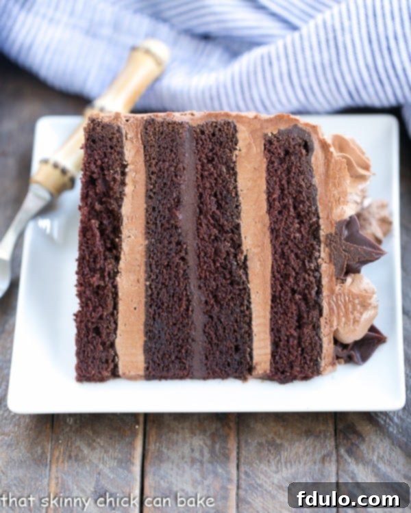 Chocolate Fudge Layer Cake slice on its side on a white square plate.