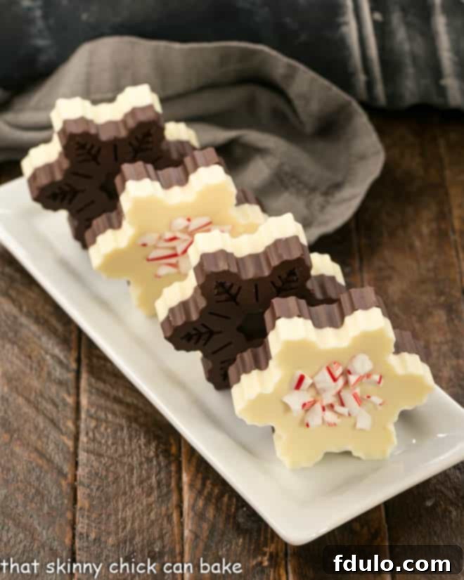 Layered Chocolate Peppermint Bark Snowflakes - A fabulous, impressive holiday or hostess gift! Layered Peppermint Bark Snowflakes arranged neatly with delicate candy cane shards on a narrow, elegant white serving tray, highlighting their festive and intricate design.