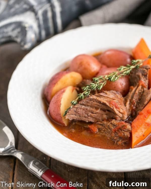 Easy Pot Roast in a shallow white bowl with a sprig of thyme.