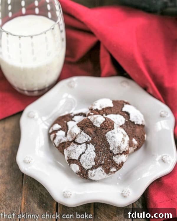Close-up of freshly baked Chocolate Crackle Cookies on a decorative white plate, showing the distinct crackle effect.