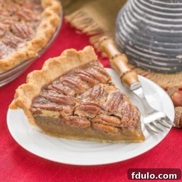 Classic Pecan Pie, with a boozy twist! - A rich, ultra-sweet indulgence. Perfect for the holidays! Classic Pecan Pie slice on a dessert plate over a red woven napkin.