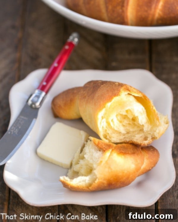 Buttery Homemade Crescent Rolls on a white plate with a red handled knife.