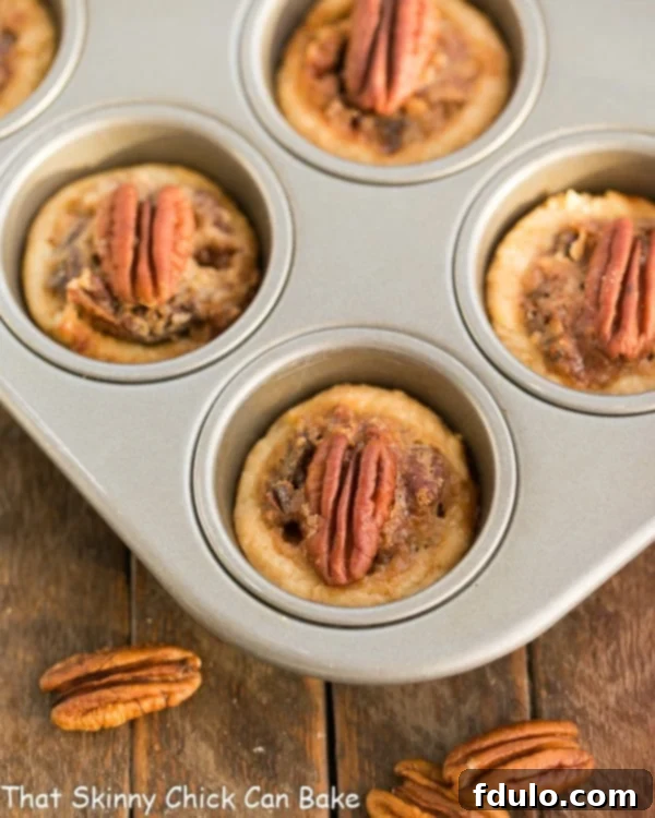 Pecan Tassies - Mini Pecan Pies that are perfectly bite-sized, incredibly flavorful, and ready to impress! A batch of freshly baked Mini Pecan Pies, or Pecan Tassies, arranged neatly in a non-stick mini muffin tin, showcasing their perfect golden crusts and rich fillings.
