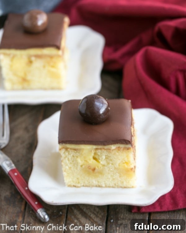 Boston Cream Pie Poke Cake brilliantly unites two culinary stars, the classic Boston Cream Pie and the innovative poke cake, into a moist, buttery confection brimming with creamy vanilla pudding and elegantly finished with a rich chocolate ganache! Two white dessert plates elegantly displaying slices of Boston Cream Pie Poke Cake, emphasizing the inviting moistness and the harmonious blend of vanilla and chocolate layers.