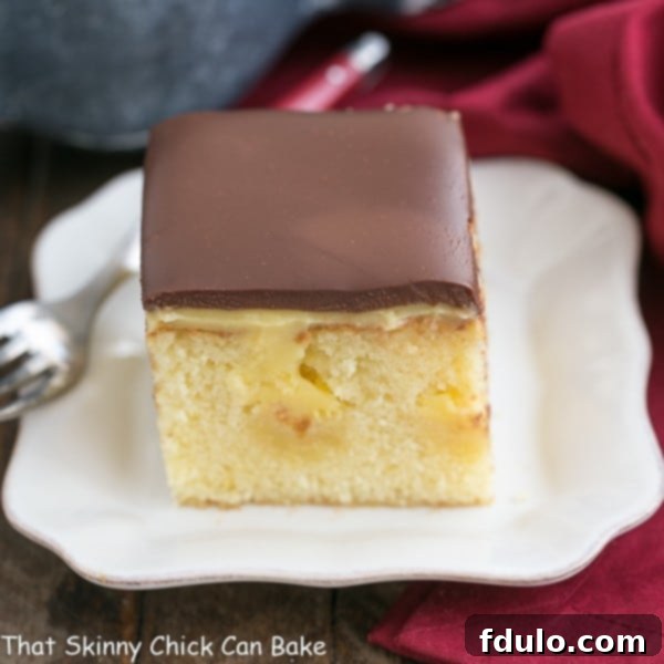 This Boston Cream Pie Poke Cake Recipe masterfully combines two fantastic desserts, Boston Cream Pie and poke cake, into a moist, buttery cake generously filled with creamy vanilla pudding and lavishly topped with rich, decadent chocolate ganache! A perfectly portioned and ready-to-eat slice of Boston Cream Pie Poke Cake presented on a clean white dessert plate, showcasing its appealing layers and smooth topping.