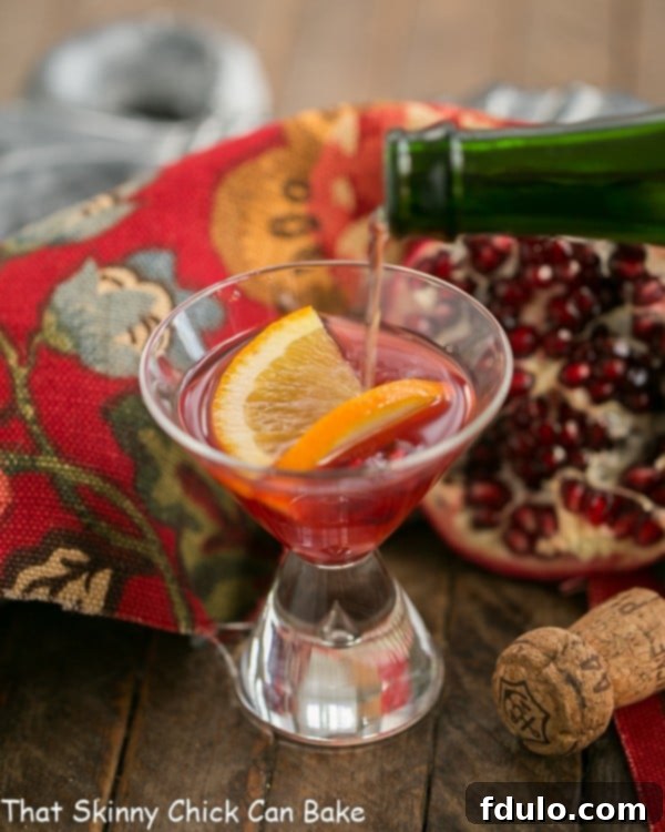 Champagne pouring into a glass of Pomegranate Champagne Cocktail, showcasing the vibrant red hue and effervescence