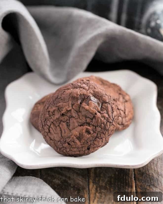 Black Gold Cookies - a culinary delight combining two types of chocolate, abundant chocolate chunks, and minimal flour for that perfect chocoholic's dream! Black Gold Cookies arranged artfully on a small white plate, highlighting their rich color and inviting texture.