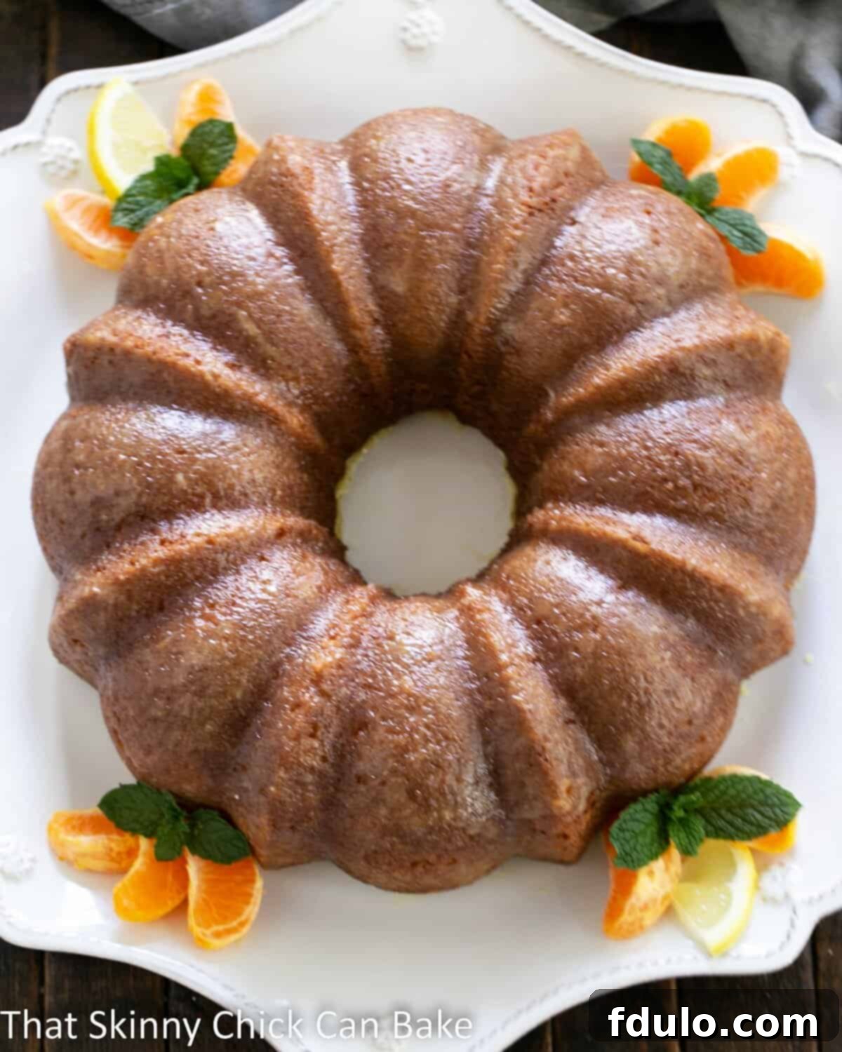 An overhead view of the Easy Lemon Bundt Cake, generously glazed and presented on a pristine white cake plate, emphasizing its enticing texture.