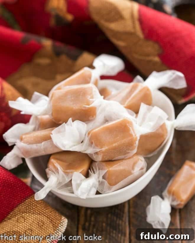 Homemade Brown Sugar Caramels individually wrapped in waxed paper, neatly arranged in a white candy bowl, highlighting their golden-brown hue and rustic charm.