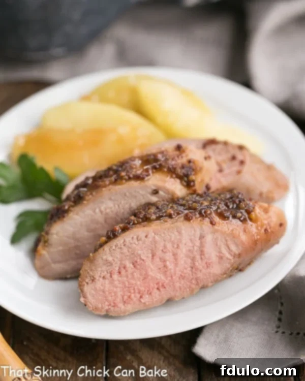 Close up of a plate of apple mustard pork tenderloin with apple slices.