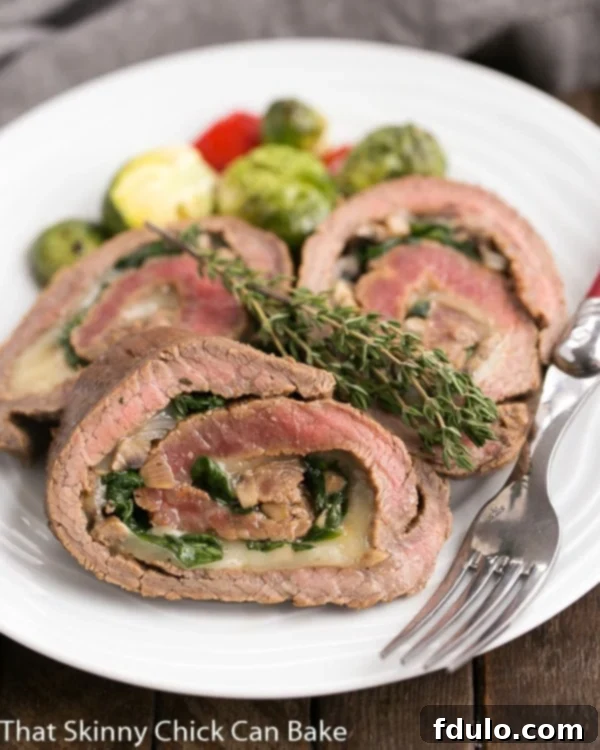 Sliced Flank Steak Roulades artfully arranged on a white dinner plate, showcasing the vibrant green spinach, earthy mushrooms, and creamy Provolone cheese within the tender, perfectly cooked beef.