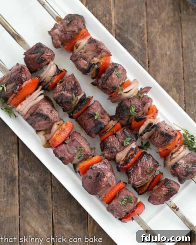 Marinated Greek Lamb Kebabs skewered on a white ceramic tray, ready for grilling, viewed from above.