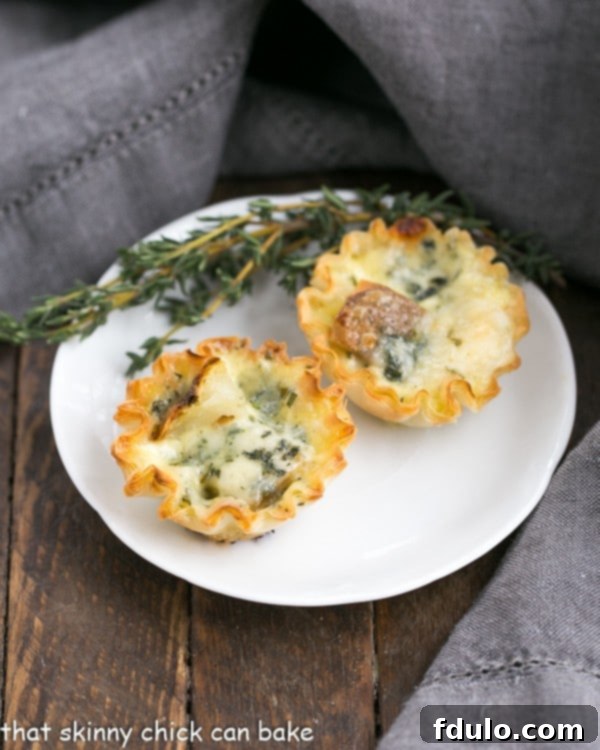 Potato Blue Cheese Tartlets are an easy, elegant and hearty appetizer! Three Potato Blue Cheese Tartlets arranged on a round white plate, garnished with a sprig of fresh thyme, highlighting their gourmet appeal.