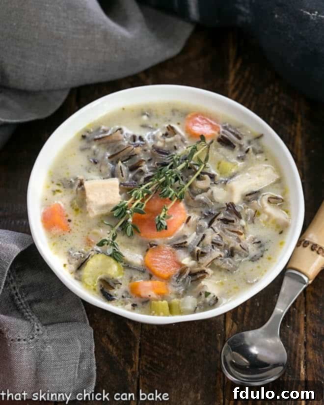 Overhead view of a bowl of wild rice soup with a bamboo handle spoon.