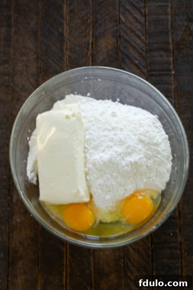 Make topping by adding cream cheese, eggs and powdered sugar a bowl.
