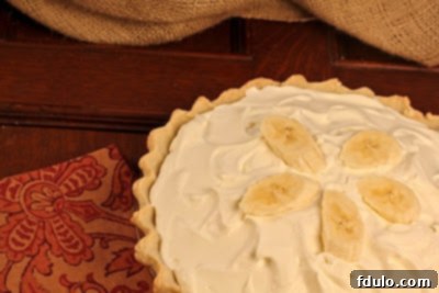 An inviting close-up of a Banana Cream Pie, highlighting the smooth, creamy texture of the filling and the delicate whipped cream.