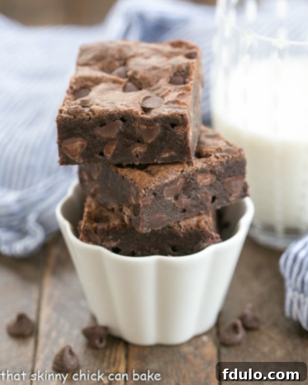 Fudgy Cocoa Brownies stacked in a fluted white ramekin.