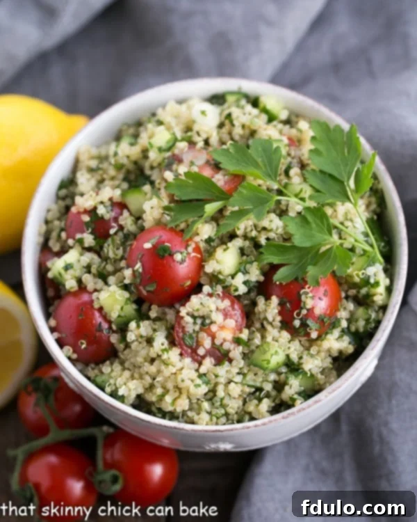 An inviting overhead photo of a white bowl generously filled with Quinoa Tabbouleh, made with quinoa instead of bulgur, highlighting the vibrant green herbs and fresh vegetables. This fresh, healthy salad is perfect for any meal.