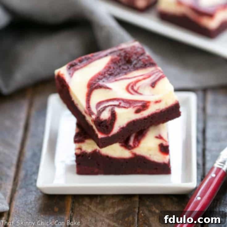 Decadent red velvet brownies with a beautiful swirled cheesecake topping.