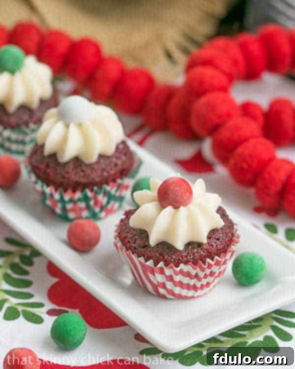 A collection of mini red velvet cupcakes adorned with cream cheese frosting, ideal for a holiday dessert spread.