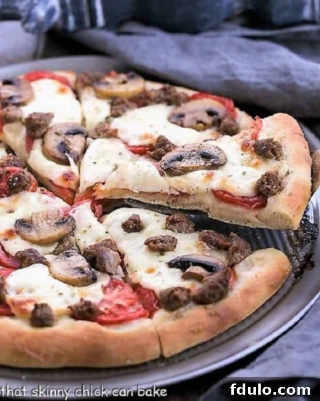 Homemade Sausage Mushroom Pizza - The ultimate comfort food with a fantastic homemade yeast dough crust. Perfect for a cozy movie night or an exciting game day gathering! Delicious Homemade Sausage Mushroom Pizza with a slice being removed from a pizza pan, showcasing the crispy crust and melted cheese.
