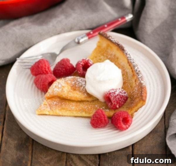 Best Dutch Baby Pancake | A puffed breakfast dish topped with berries, whipped cream and powdered sugar!