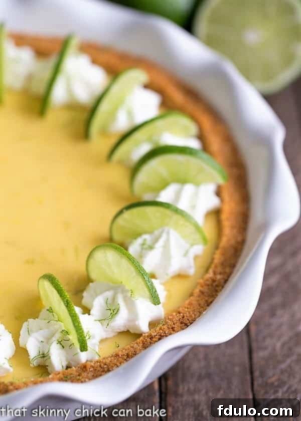 Close up view of the vibrant green Key Lime Pie filling contrasting with the golden graham cracker crust in a white pie plate.