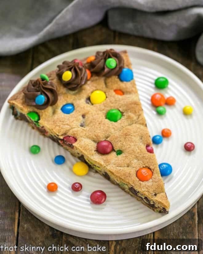 An inviting overhead shot of the full, round Chocolate Chip Cookie Cake with M&M's, showcasing its generous size and colorful topping, ready to be sliced and enjoyed.