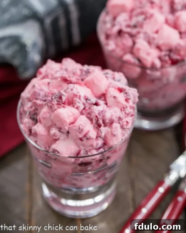 Elegant glass dishes filled with Cranberry Fluff Salad, garnished with whole cranberries, ready to be served.