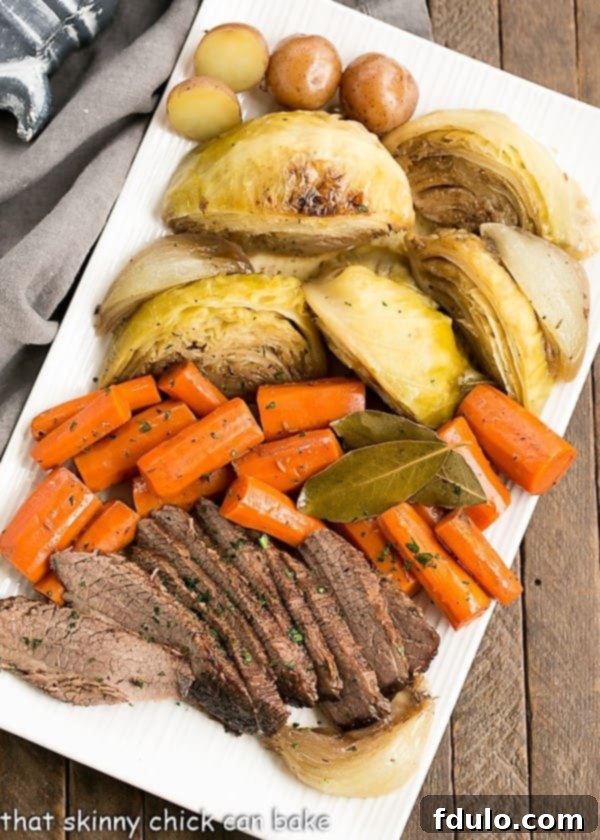 Braised Corned Beef and Cabbage starts with an uncured brisket flat instead of the already seasoned corned beef. Taking brisket, seasoning it and slow cooking with the traditional vegetables makes for an out of the ordinary St. Patrick's Day Irish corned beef recipe! #stpatricksday #recipe #irishrecipe An inviting overhead photo displaying a generous platter of Irish Braised Corned Beef, beautifully arranged with tender slices of brisket, vibrant carrots, perfectly cooked cabbage wedges, and wholesome potatoes, ready for a family meal.