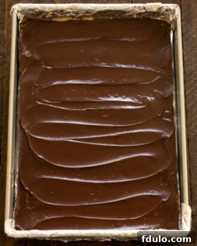 Chocolate ganache spread over the peanut butter layer of the brownies.