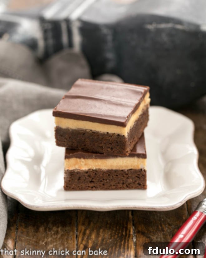 Peanut Butter Truffle Brownies stacked on a square white plate, showing the three distinct layers