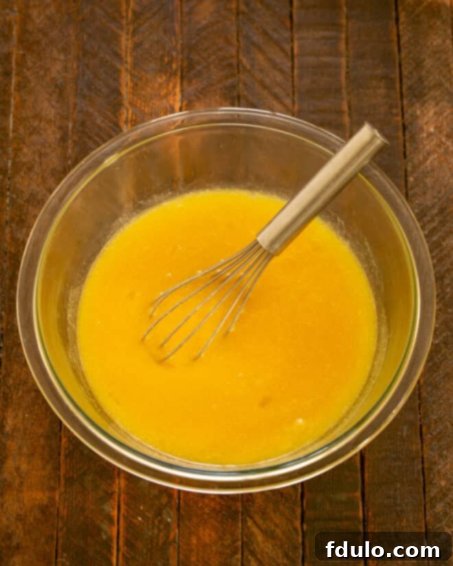 Melted butter in a bowl with sugar, eggs, and vanilla nearby.