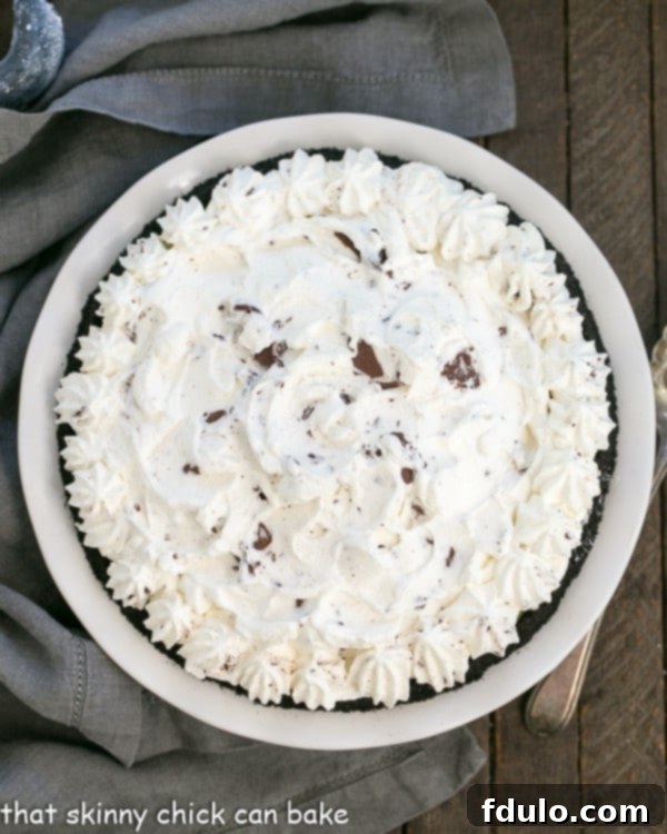 An inviting overhead view of a whole Triple Chocolate Layer Pie Recipe, beautifully garnished with chocolate-swirled whipped cream, ready to be sliced and enjoyed.