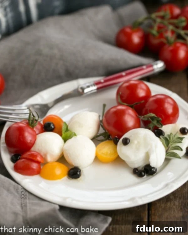 Side view of a Burrata Caprese Salad on a white plate with a fork