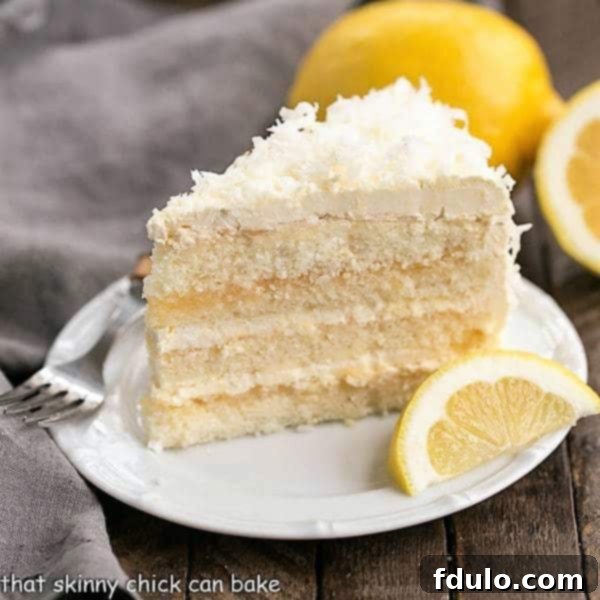 A delectable slice of Lemon Layer Cake with Lemon Curd Filling served on a white ceramic plate, garnished with a fresh lemon wedge.