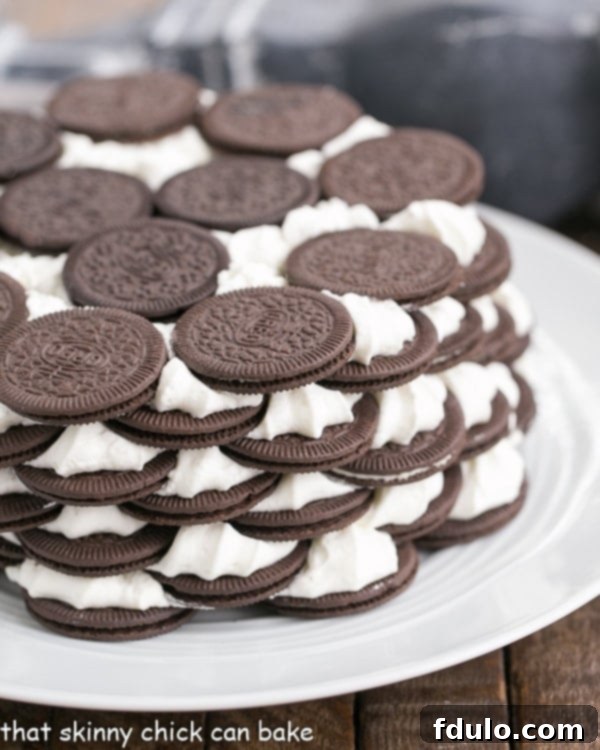 Oreo Icebox Cake - Minimal ingredients and effort to make this marvelous no-bake dessert A beautifully presented Oreo Icebox Cake on a white serving plate, garnished with crumbled Oreos and a hint of chocolate drizzle.